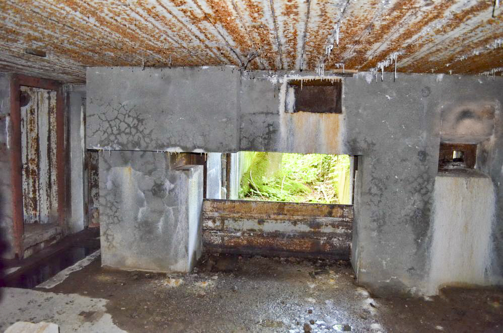 Ligne Maginot - Blockhaus STG 105 - Breitenhag - Entrée matériel fermée avec des rails. A gauche l'entrée des hommes avec les toilettes et sa fosse, à droite le créneau de tir FM de la chambre de tir mitrailleuse  nord. Au sol, entre l'entrée matériel et le créneau de tir FM, on distingue l'arrivée des câbles.