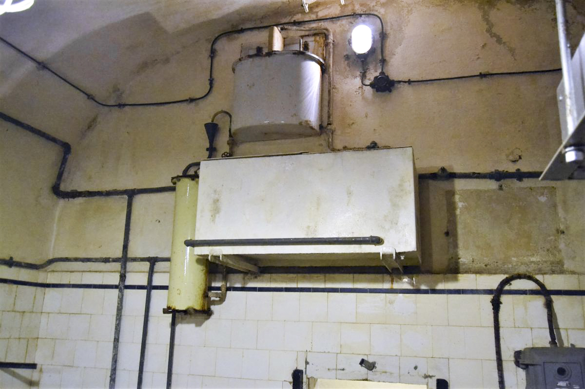 Ligne Maginot - GALGENBERG - A15 - (Ouvrage d'artillerie) - La cuisine troupe
Installation carbone-chlore de traitement de l'eau. La partie supérieure est le système de dosage du chlore. Une fois le mélange fait, celui ci passe au travers du filtre à charbon actif (tube sur la gauche de la photo) puis est stocké dans la citerne de couleur blanche en bas de la photo