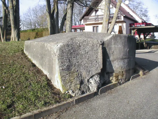 Ligne Maginot - D785 - HELFRANTZKIRCH 2 - (Blockhaus pour canon) - Le mur en pente qui protège le créneau à la vue de l'ennemi a été détruit pour construire la route, seul en subsiste un morceau.